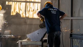 A man grinds an access cover in a foundry