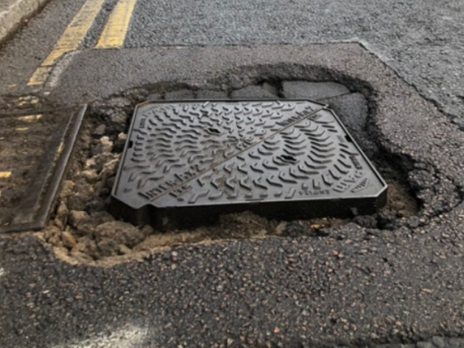 A manhole cover with infill surround failure forming a pothole