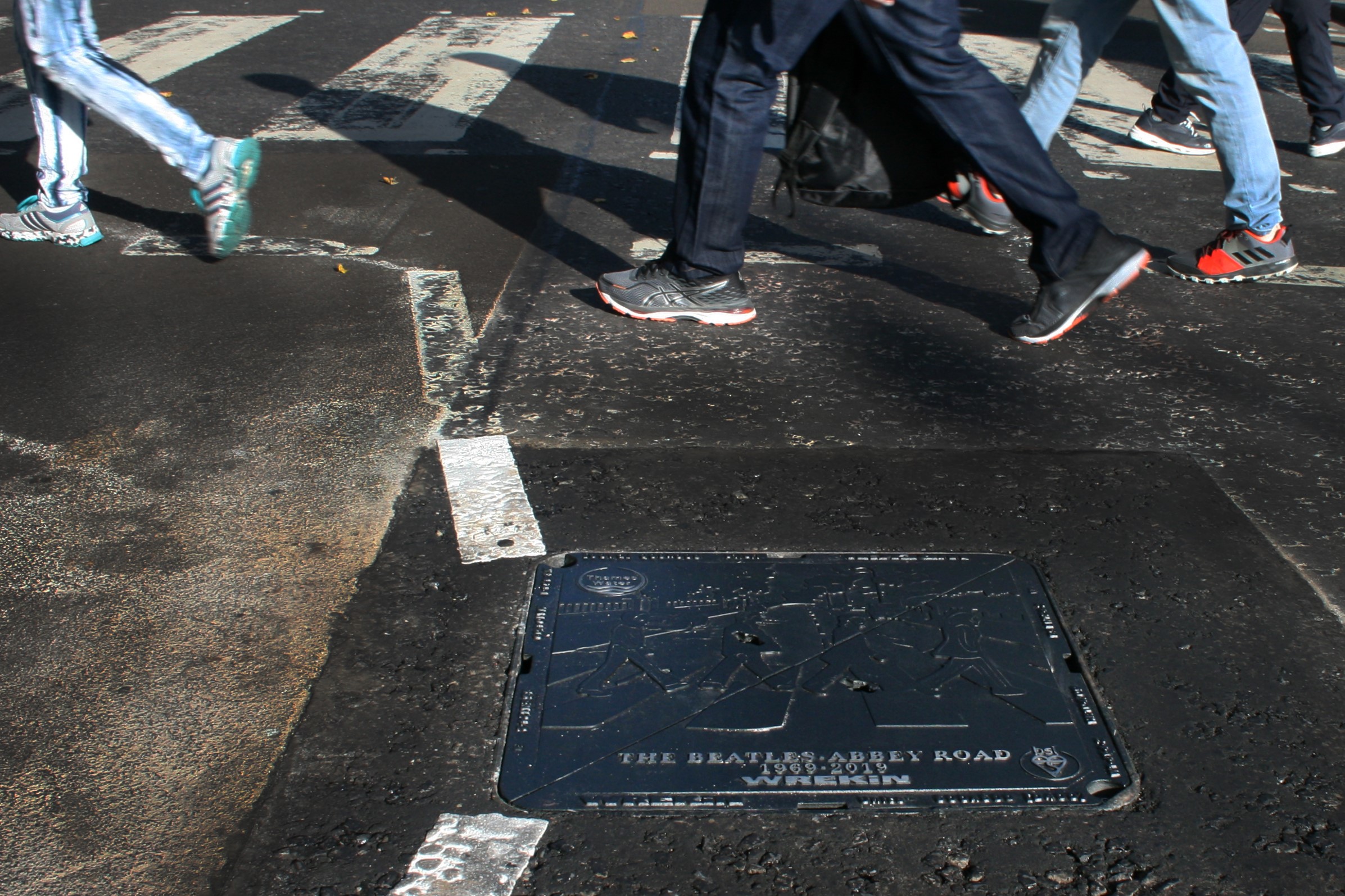 Pedestrians walking near Abbey Road manhole cover