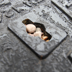 Manhole cover keyway blocked with stones and debris