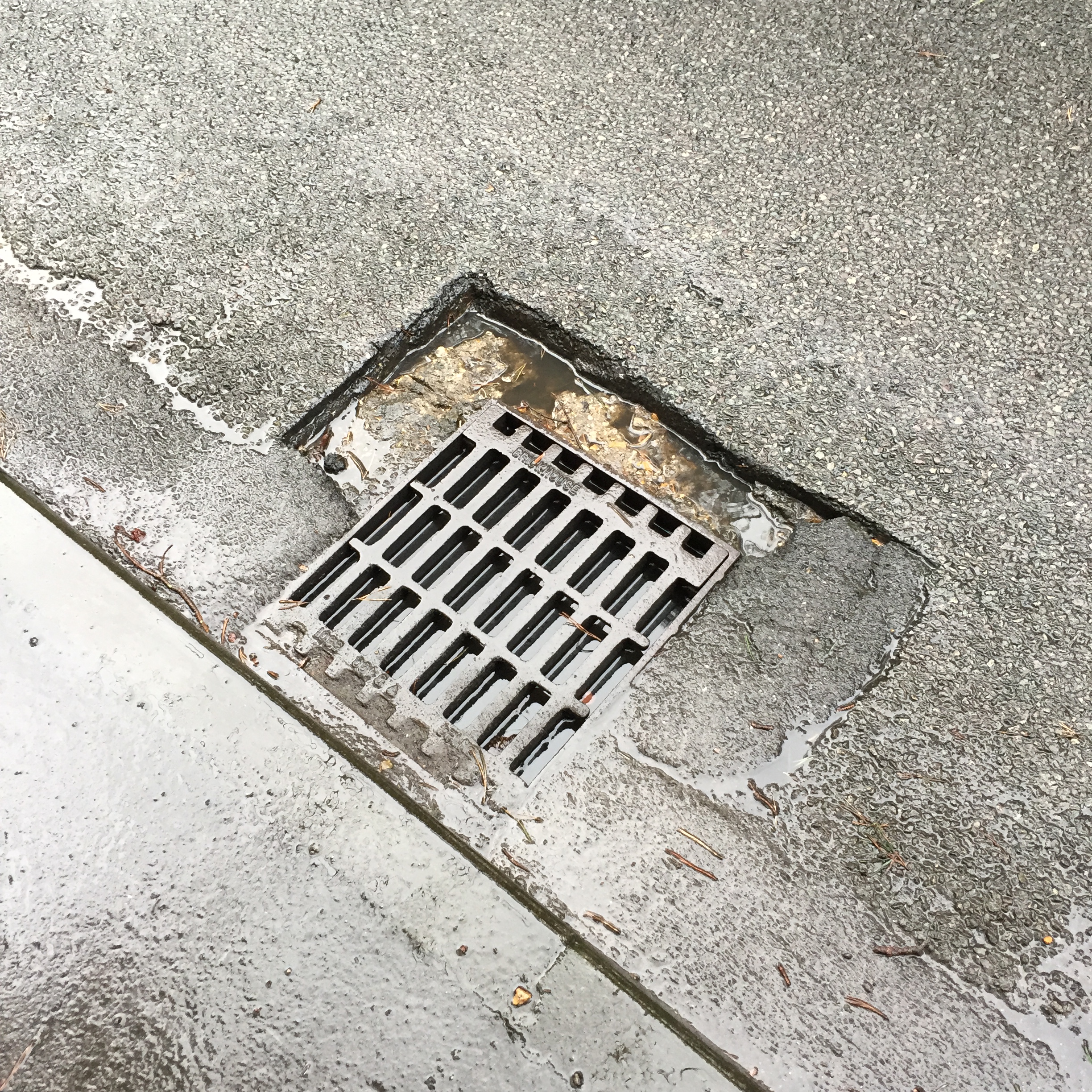 A gully grating with failure of the infill material, allowing a pothole to form