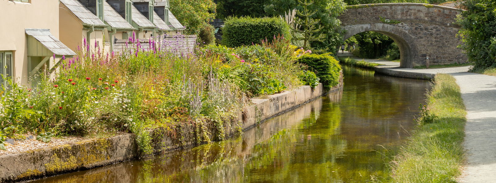 Canal beside cottages with a bridge passing over it in the distance