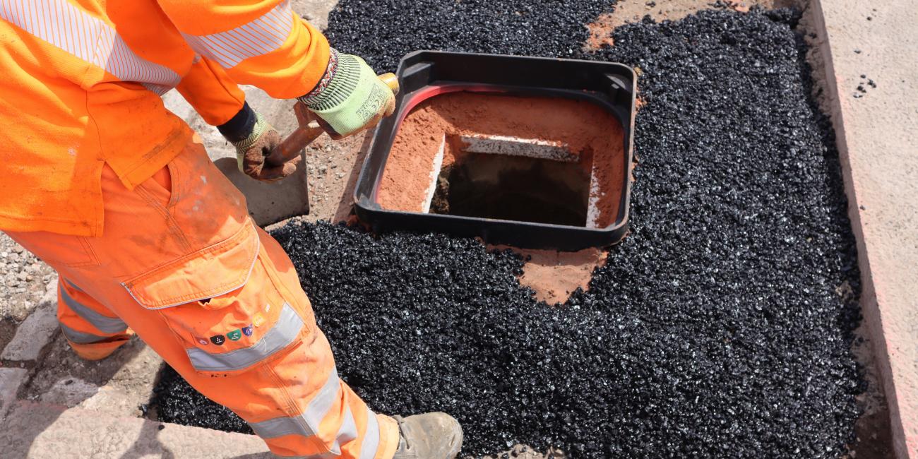 Back filling a manhole cover frame with tarmac