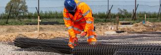Man working with Geogrid roll at Norwich North Recycling Centre