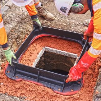 Unite manhole cover frame being installed by two workers