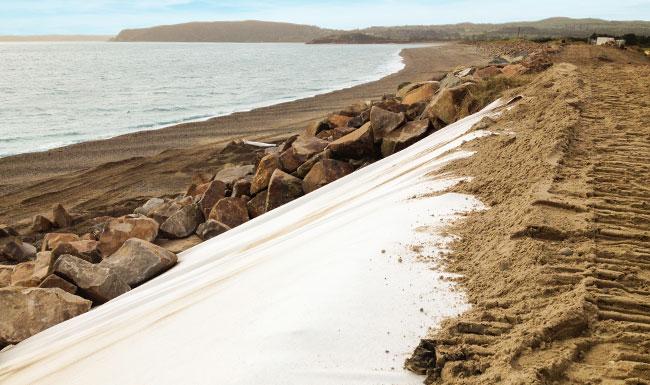 Non woven geotextiles being installed as part of a coastal defence system