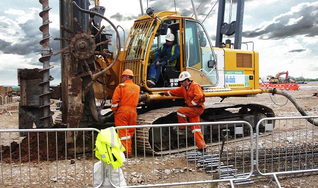 Two people installing a piling rig on construction site