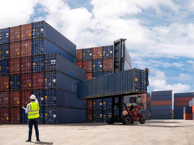 A dock yard with a forklift truck moving a container